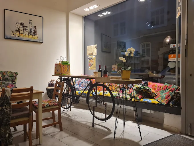 Gastraum des D'ouro mit Fahrrad-Tisch, bunt gemusterten Kissen auf der Fensterbank und Orchidee