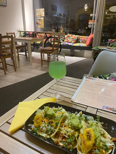 Drei Tacos mit Guacamole auf schwarzer Platte, daneben ein grüner Cocktail